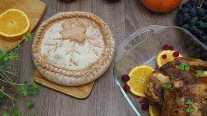a woman is preparing a festive dinner at home. chicken with oranges. On the table there is pie and fruits, grapes, apples, pumpkin. Roasted Turkey. Thanksgiving table served . Christmas dinner