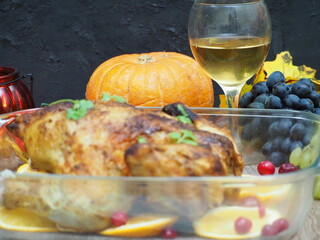a woman is preparing a festive dinner at home. chicken with oranges. On the table there is pie and fruits, grapes, apples, pumpkin. Roasted Turkey. Thanksgiving table served . Christmas dinner