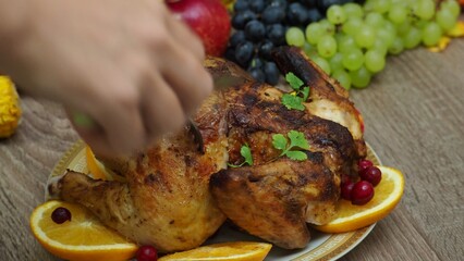 a woman is preparing a festive dinner at home. chicken with oranges. On the table there is pie and fruits, grapes, apples, pumpkin. Roasted Turkey. Thanksgiving table served . Christmas dinner