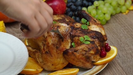 a woman is preparing a festive dinner at home. chicken with oranges. On the table there is pie and fruits, grapes, apples, pumpkin. Roasted Turkey. Thanksgiving table served . Christmas dinner