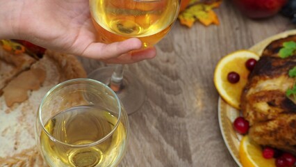 toasting with wine glasses in front of chicken dinner, pour wine, festive dinner at home. chicken. pie, fruits, grapes, apples, pumpkin. Roasted Turkey. Thanksgiving table served . Christmas dinner