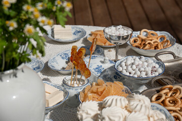 Assorted traditional Russian sweets displayed on elegant porcelain dishes: lollipops, zefir, marmalade, sugar-coated berries, bagels, and marshmallows
