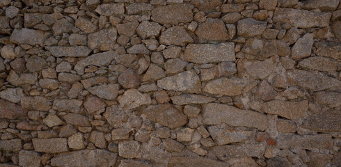 Rustic stone wall with multicolored natural rocks and mortar