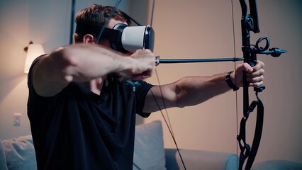Man holding bow and arrow. Man bowing with a headset in the vr. Archery technology is a virtual indoor game. A person grasping a bow and arrow lifestyle.