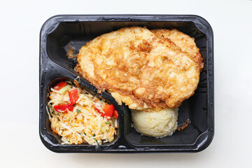 Takeaway meal in plastic box. Fried cutlet with mashed potatoes and salad. Lunch food delivery portion. Fast food container isolated on white background. Ready to eat homemade dinner concept.