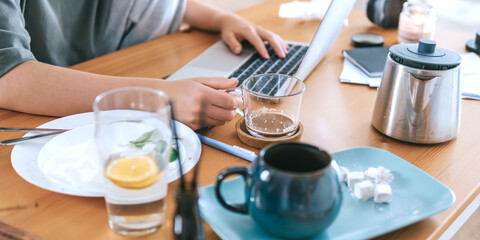  Gen Z woman working from home at cozy kitchen table with laptop and phone. Digital nomad lifestyle, mindfulness, remote work, balance, mental calm and modern freelancing