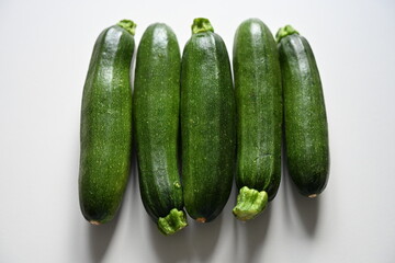 Fresh green zucchinis on white background. Perfect for concepts of healthy eating, vegan diet, weight loss, detox, wellness lifestyle, organic vegetables and plant-based food.