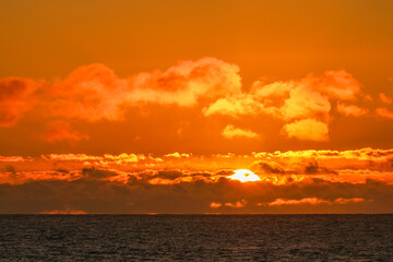 Fototapeta premium Aerial panoramic view of sunset over ocean. Nothing but sky, clouds and water. Dramatic picturesque evening scene. Ocean and colorful cloudy sky in the background. Nature landscape. Travel background