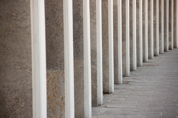 Series of vertical concrete columns with white accents create a rhythmic pattern along a modern...