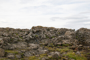 Rocky landscape with mossy ground under a cloudy Icelandic sky
