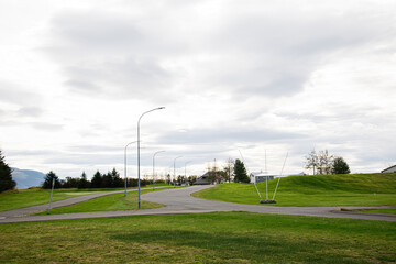 Obraz premium Scenic suburban street with lush greenery and cloudy sky in Iceland