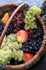 Basket of fruits. Grapes, apples, and pears in a basket on a tree stump. Beautiful natural background. Grapes. Fruit background. Still life. Harvesting. Fresh, juicy fruits. Vitamins. Food.
