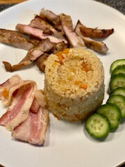 Garlic fried rice with bacon and grilled pork neck, cucumber garnish, homemade meal close-up 