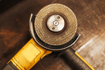 Angle grinder closeup. Industrial power tool on workshop table. Yellow hand machine with grinding disc. Carpentry or metalwork equipment. Construction workshop scene. Professional tool concept.