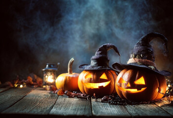 Three carved pumpkins with witch hats and glowing faces on a wooden surface for Halloween.