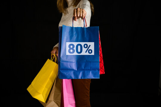 Woman holding shopping bags with 80% discount sign, ready for consumer savings