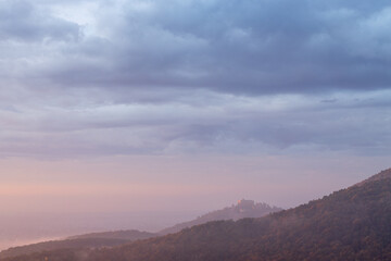 Hambacher Schloss im herbstlichen Sonnenaufgang mit Nebel und Wolken über dem Pfälzerwald