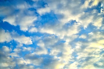 clouds of different shapes in the blue sky illuminated by the sun's rays