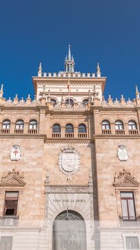 Timelapse of the Cavalry Academy facade in Plaza de Zorrilla, Valladolid, Spain. Historic military building with intricate architecture, surrounded by a busy urban scene under a blue sky with clouds.