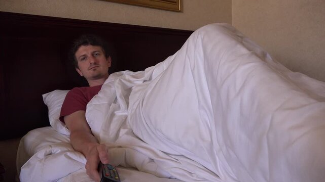 Man laying in hotel bed watching TV 4K