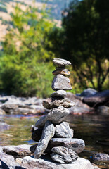 Cairn of stones balanced on the river in sunny day