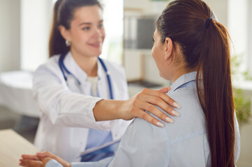 Obraz premium Positive female doctor or nurse providing help and support to a woman patient during a consultation in the hospital office. Focusing on aid and healthcare to ensure patient well being.