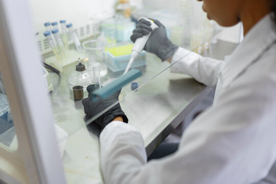 Scientist using micropipette with test tubes in biosafety laboratory