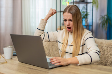 Caucasian woman at home on table working on laptop, virus error, lost data, screen, tapping keys, feeling anxious, desperate, needing fix. Girl appears confused, frustrated, holding head, seeking help