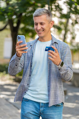 Smiling man using credit card smartphone while transferring money, purchases online shopping, order...