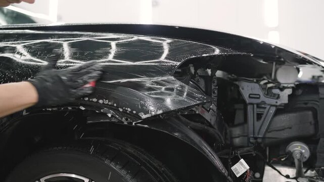 Car detailer applying ceramic coating on black car
