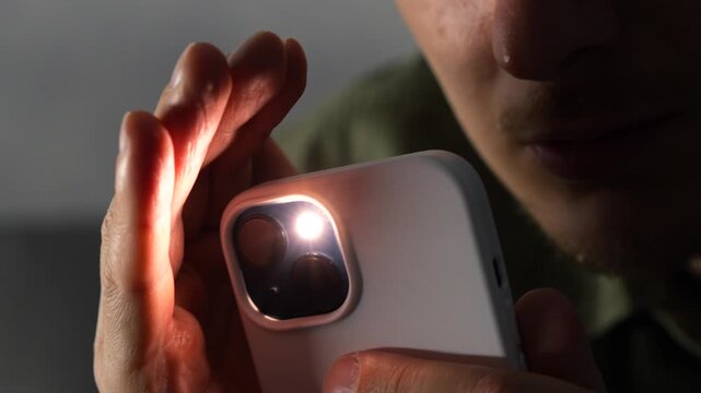 Bright light from a smartphone's flashlight.
The flashlight illuminates a person and a dark room.
Close-up of a person lighting their way with a smartphone's flashlight.
Shine, smartphone, bright