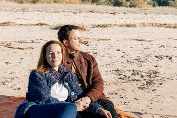 Portrait loving couple walks on beach along sea on sunny autumn day. Weekend and lifestyle concept. High quality photo