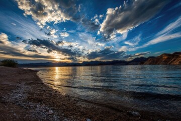 Obraz premium Dramatic sunset over a calm lake. Sandy shore, dramatic clouds, vibrant colors