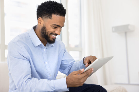 Smiling young man resting on sofa with digital tablet