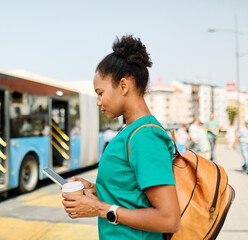 Nurse iwalking down the street  and using a mobile phone outside  waiting for transportation or...