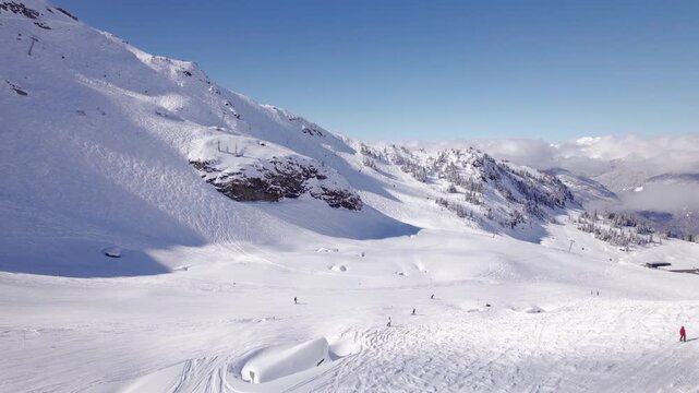 Downhill skiers with mountain vista, aerial footage, ski mountain, sunny day, winter, ski hill, Whistler BC. 5.4K 24FPS