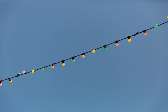 Guirlande lumineuse multicolore style guinguette sur fond de ciel bleu