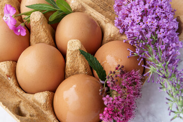 Brown eggs and flowers in a carton.