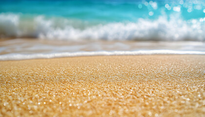 Close-up view of tropical beach sand with turquoise ocean waves crashing gently in background under clear blue sky. Soft, textured