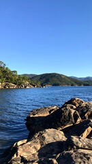 Calm lake shore with rocks and hills
