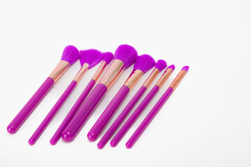Naklejka premium A set of purple makeup brushes. The brushes are purple and have a gold trim. They are arranged in a row on a white background