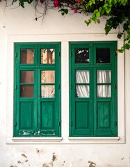 Fototapeta premium Two antique green wooden windows on a weathered white wall
