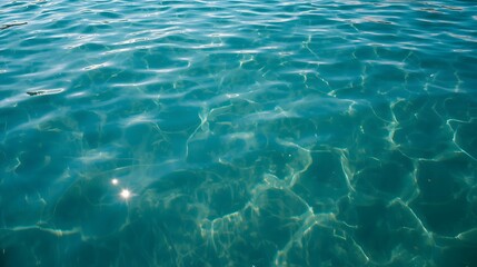 Clear turquoise sea water surface with sunlight reflections, symbolizing marine clarity, freshness, natural purity, ocean tranquility, tropical beauty, and aquatic background concept