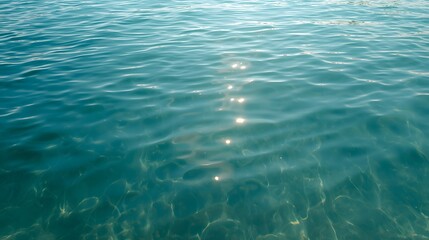Fototapeta premium Clear turquoise sea water surface with sunlight reflections, symbolizing marine clarity, freshness, natural purity, ocean tranquility, tropical beauty, and aquatic background concept