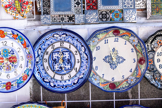 A collection of blue and white plates with clocks on them. The plates are arranged in a row and the clocks are set to different times. City of Puebla, Mexico, crafts
