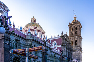 A large building with a clock tower and a cross on top. The building is in a foreign country. City...