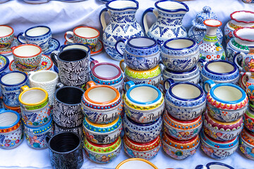 A table full of colorful ceramic cups and bowls. The cups and bowls are of various shapes and sizes. City of Puebla, Mexico, crafts