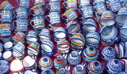 Fototapeta premium A collection of colorful cups and bowls with various designs and messages written on them. The cups and bowls are arranged in a row, with some of them being upside down. City of Puebla, Mexico, crafts