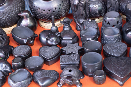 A collection of black ceramic items, including a heart, a turtle, and a star. The items are arranged on a table, and the overall mood of the image is one of warmth. City of Puebla, Mexico, crafts