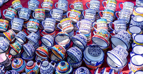 Fototapeta premium A large collection of colorful cups with Hebrew writing on them. The cups are arranged in a pile on a table. City of Puebla, Mexico, crafts